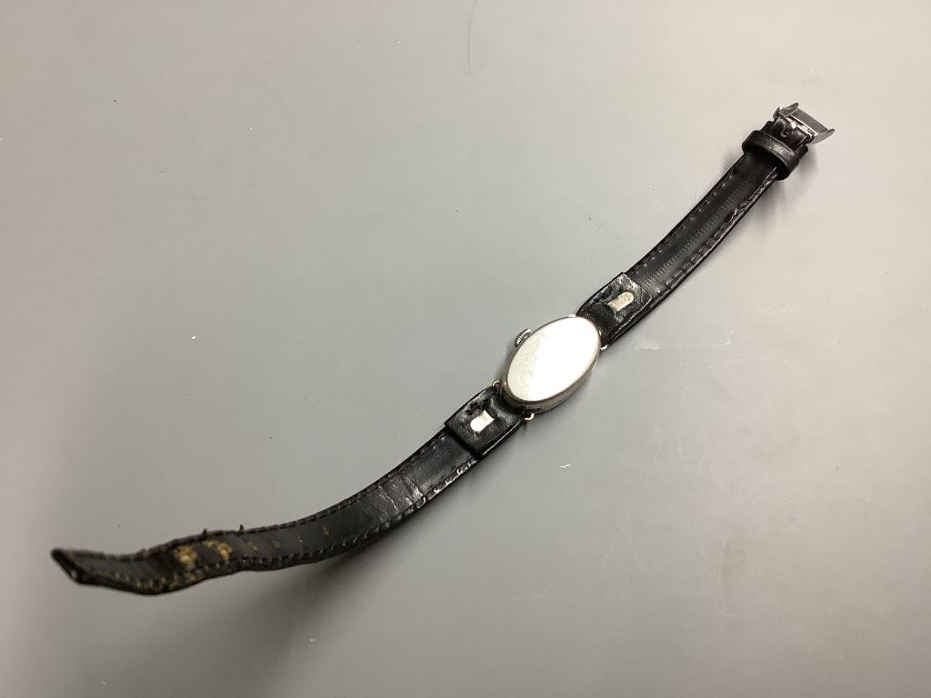 A lady’s mid 20th century white metal stamped platine and diamond set oval cocktail watch, on a leather strap.